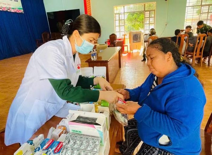  Cán bộ quân y hướng dẫn người dân sử dụng thuốc. Ảnh: Yshih 