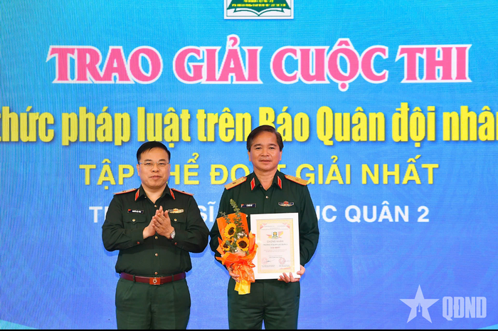Thiếu tướng Nguyễn Việt Dũng, Cục trưởng Cục Pháp chế Bộ Quốc phòng, đồng Trưởng ban chỉ đạo Cuộc thi trao giải Nhất tập thể năm của Cuộc thi “Tìm hiểu kiến thức pháp luật” trên Báo QĐND năm 2025 tặng đại diện Trường Sĩ quan Lục quân 2. Ảnh: HÁN TRANG