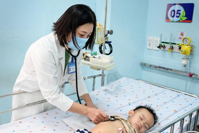  Bác sĩ đang kiểm tra nhịp tim và các dấu hiệu sinh tồn cho một bệnh nhi mắc tay chân miệng độ 2B. Trong phân độ lâm sàng, độ 2B được coi là "ngưỡng cửa" nguy hiểm, báo hiệu virus đã bắt đầu tấn công vào hệ thần kinh trung ương. Ở giai đoạn này, trẻ thường xuất hiện các dấu hiệu như giật mình chới với kèm theo tình trạng quấy khóc, lờ đờ hoặc sốt cao khó hạ. Sau khi xuất hiện biến chứng co giật, bé trai đã được đưa vào khu vực theo dõi sát để ngăn chặn nguy cơ chuyển nặng sang độ 3 hoặc độ 4. 