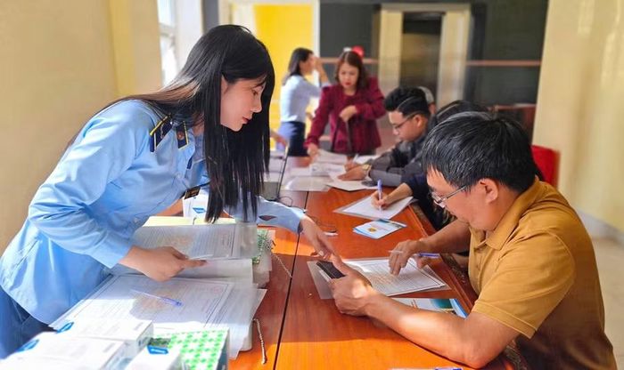 Nhân viên QLTT hướng dẫn doanh nghiệp ký cam kết bảo đảm an toàn thực phẩm và thực hiện niêm yết giá theo quy định. Ảnh: B.N