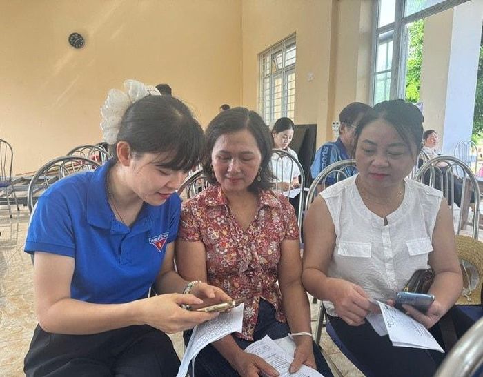 Đoàn thanh niên xã Ứng Hòa hỗ trợ người dân cài đặt ứng dụng giải quyết thủ tục hành chính trên nền tảng số. Ảnh: Phùng Lương