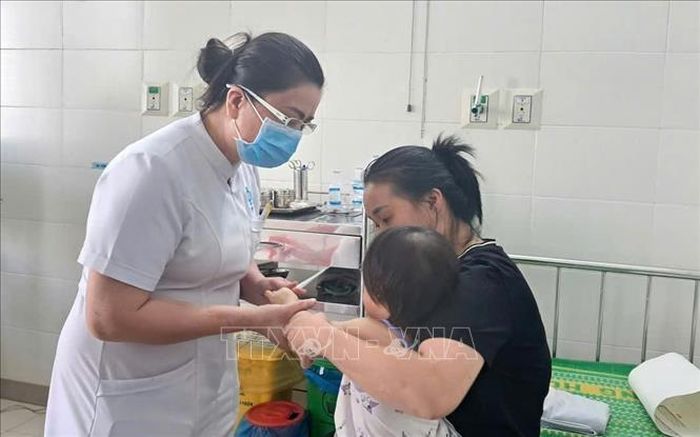 Y tá Bệnh viện Sản - Nhi Quảng Ngãi kiểm tra cho trẻ bị bệnh tay chân miệng.