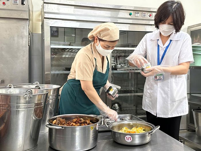 Nhân viên y tế cùng nhà bếp thực hiện lưu mẫu thức ăn hằng ngày tại bếp ăn bán trú trường tiểu học Núi Thành. Ảnh: H.T