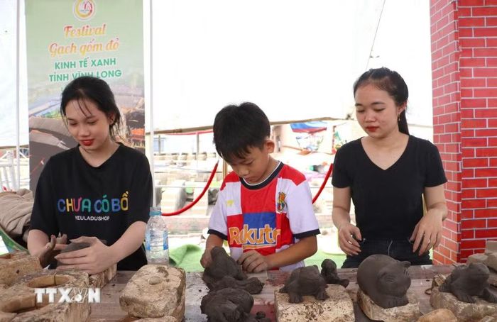 Các bạn trẻ tham gia hoạt động trải nghiệm sản xuất quà tặng gốm đỏ Vĩnh Long. (Ảnh: Lê Thúy Hằng/TTXVN)