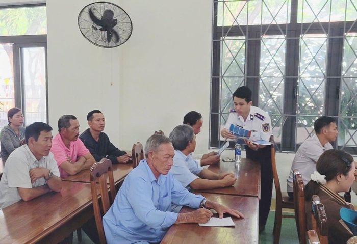 Cảnh sát biển phát tờ rơi cho ngư dân tham dự buổi tuyên truyền. Ảnh: HẢI ĐĂNG