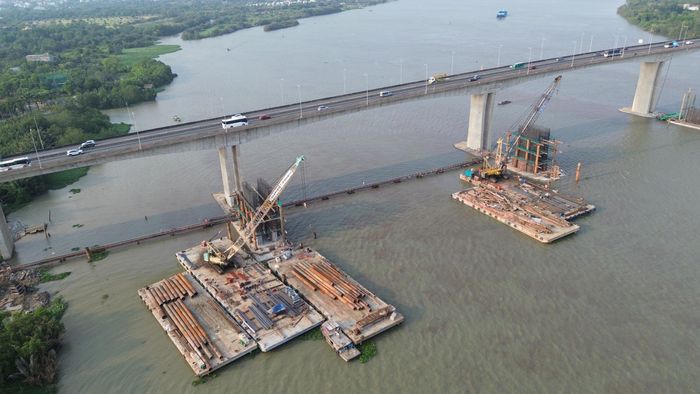 Phía bờ TP.HCM, trên công trường, nhà thầu đang bố trí 28 mũi thi công, 6 mũi thi công triển khai làm các hạng mục đúc dầm, cấu kiện bê tông. Nhiều sà lan công suất lớn "cõng" loạt thiết bị, máy móc triển khai các hạng mục dưới sông.