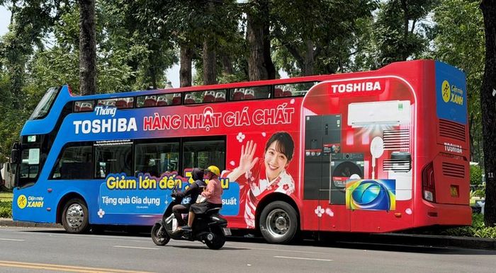 Thương hiệu Điện Máy Xanh quảng cáo phía sau xe buýt thoáng nóc đậu trên đường Phạm Ngọc Thạch, phường Sài Gòn