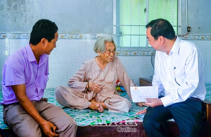 Ðồng chí Huỳnh Văn Thẳng, Bí thư Ðảng ủy xã An Trạch (bìa phải) và ông Nguyễn Minh Ðang, Phó Chủ tịch UBND xã (bìa trái), thăm hỏi cụ Nguyễn Thị Bảy, gia đình cụ từng che chở cán bộ cách mạng trong kháng chiến.