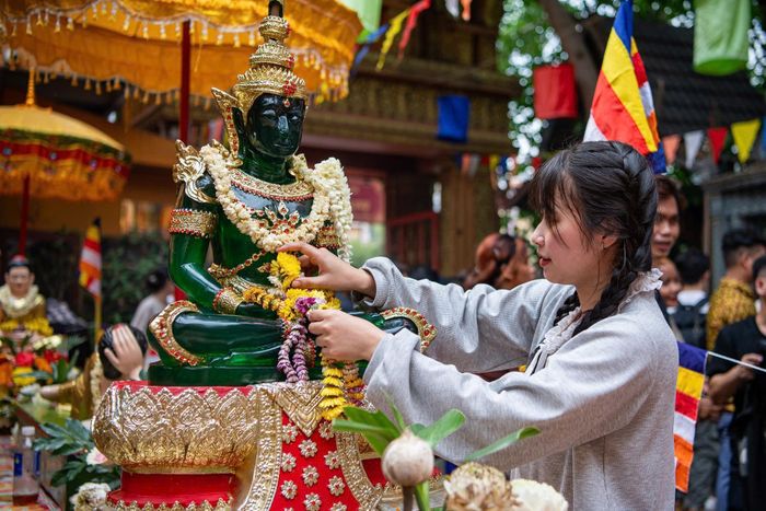 Sau phần nghi lễ của chư Tăng, các Phật tử lần lượt xếp hàng, nhẹ nhàng dùng hoa vẩy nước lên tượng Phật, gửi gắm ước nguyện về sự bình an, may mắn cho bản thân và gia đình. Ảnh: Hải Nhi