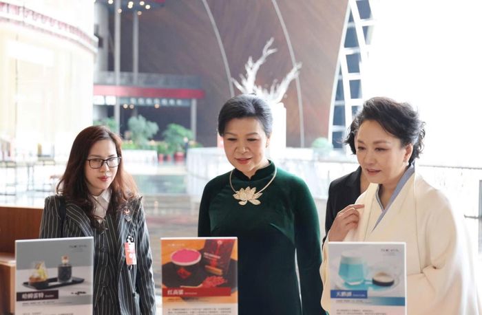 Hai phu nhân trải nghiệm khu tự phục vụ có robot pha cà phê. Ảnh: TTXVN