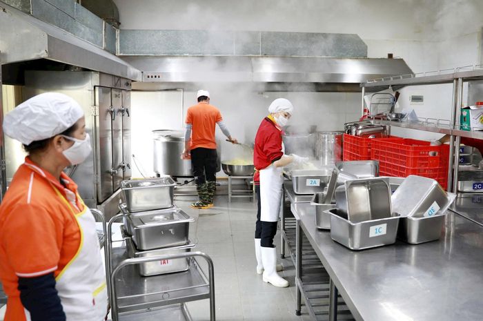 Nhân viên bếp ăn thực hiện nghiêm ngặt việc bảo đảm vệ sinh an toàn thực phẩm trong quá trình chế biến thức ăn tại Trường Tiểu học Trần Quốc Toản (phường Hoàn Kiếm). Ảnh: Quang Thái