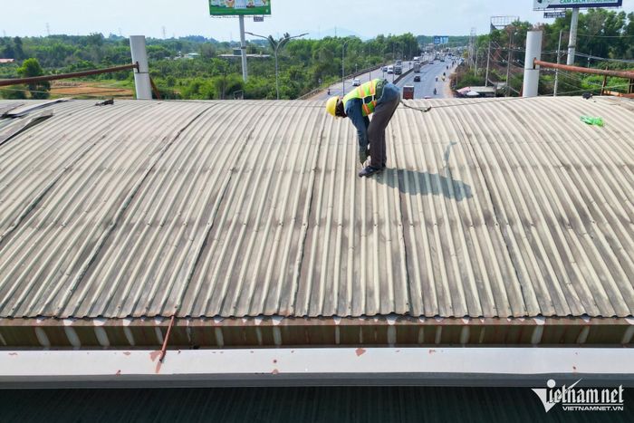Một công nhân đang kiểm tra và tháo dỡ mái tôn trạm thu phí T2.