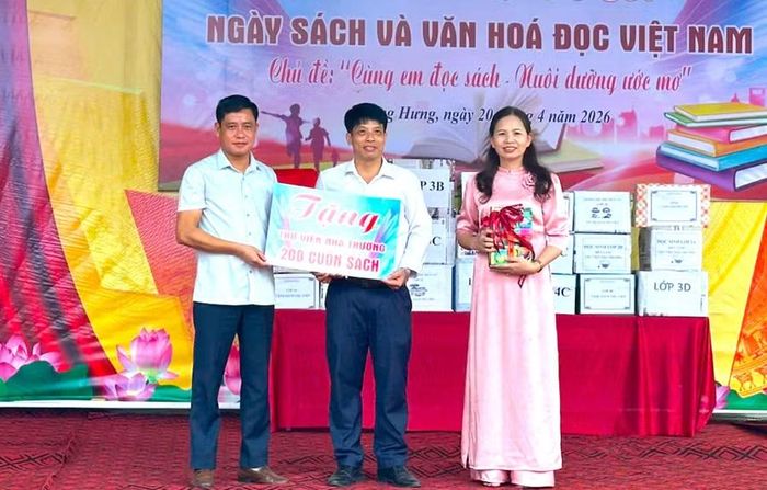 Ông Bùi Ngọc Hướng (bên trái) Phó Chủ tịch Thường trực UBND xã Quang Hưng trao tặng sách cho Trường Tiểu học Trần Cao.