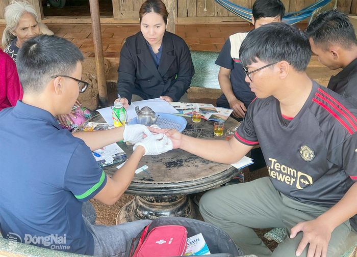 Anh Tạ Văn Niệm, tình nguyện viên Tổ chức Health Poverty Action (HPA) tại Việt Nam, phụ trách Dự án “Phòng chống sốt rét cho dân di biến động” tại xã Đăk Ơ, xét nghiệm sốt rét cho người dân. Ảnh: Ngọc Thảo