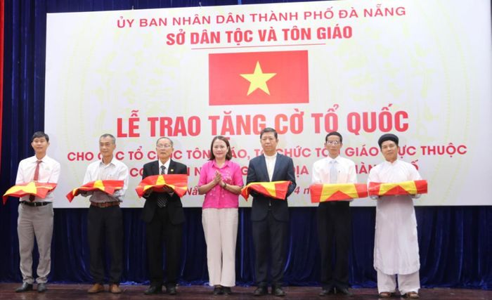 Phó Chủ tịch Ủy ban MTTQ Việt Nam thành phố Trần Thị Mẫn (giữa) trao cờ Tổ quốc cho các cơ sở tôn giáo, tín ngưỡng. Ảnh: HOÀNG LIÊN