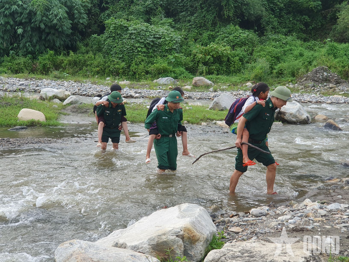 Cán bộ, chiến sĩ Bộ đội Biên phòng tỉnh Lào Cai cõng các cháu học sinh qua suối. Ảnh: LÊ QUANG