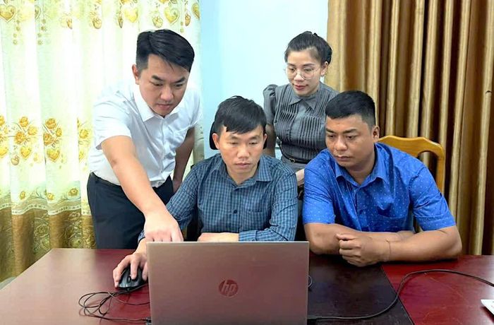 Đồng chí Phan Trần Tuấn Anh (thứ nhất, từ trái sang), Trưởng ban Xây dựng Đảng xã Dân Hóa hướng dẫn cán bộ sử dụng sổ tay đảng viên điện tử - Ảnh: Q.N