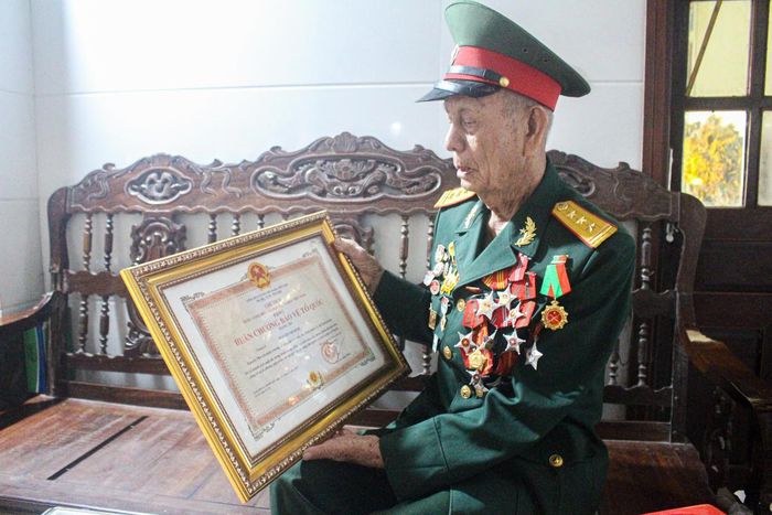 Thượng tá, thương binh Nguyễn Minh Đệ xem lại Huân chương Bảo vệ Tổ quốc, phần thưởng ghi nhận những năm tháng cống hiến của ông trong quân ngũ. Ảnh: Cẩm Kỳ 