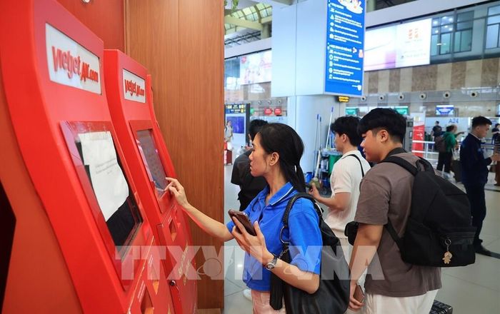Người dân làm thủ tục "check-in" tại quầy làm thủ tục tự động của hãng hàng không VietJet Air, nhà ga T1 cảng hàng không quốc tế Nội Bài. Ảnh: Quốc Khánh - TTXVN