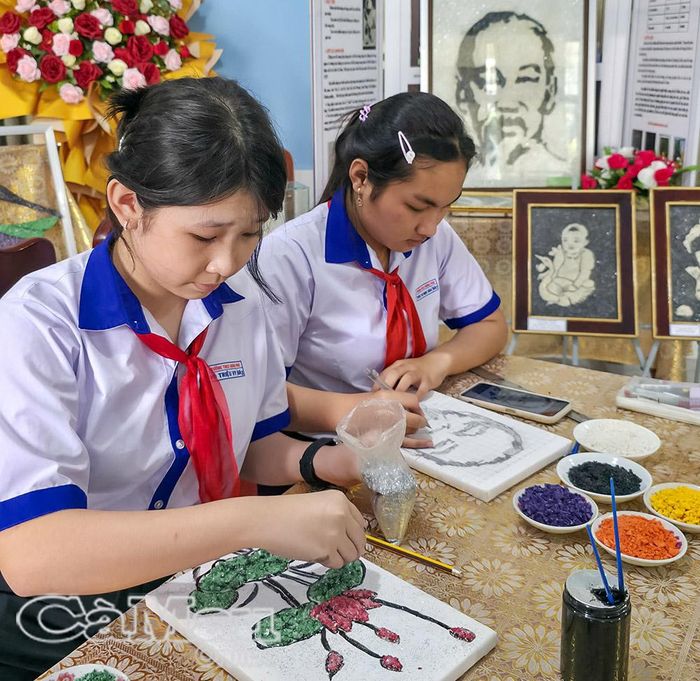 Thành viên Câu lạc bộ Mỹ thuật Trường THCS Hưng Phú tỉ mỉ đính từng hạt muối đã nhuộm màu lên nền tranh.