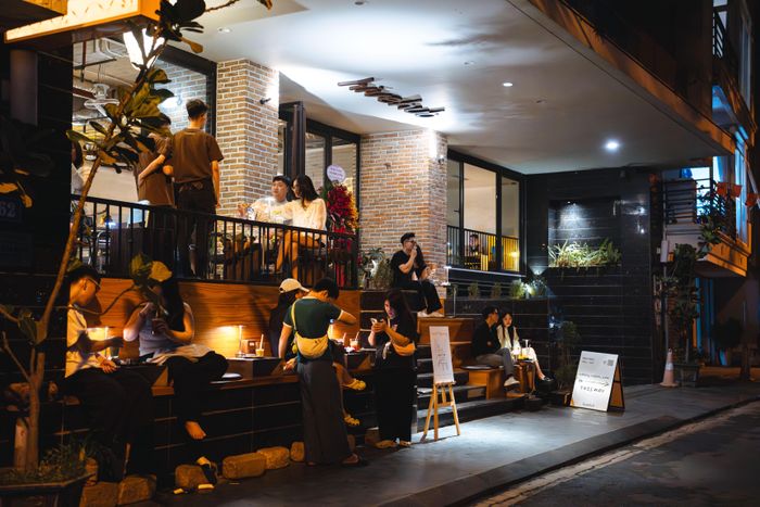 Bước sang khung giờ 17-18h, không gian bắt đầu chuyển trạng thái từ quán cà phê sang "vang vỉa". Ánh sáng tự nhiên giảm dần, hệ thống đèn được điều chỉnh theo hướng dịu hơn, trong khi thực đơn mở rộng sang rượu vang và các món ăn phù hợp. Tệp khách buổi tối nghiêng về nhóm nhỏ và cặp đôi, với trải nghiệm thư giãn, riêng tư hơn so với ban ngày. Không gian ngoài trời, sát vỉa hè với tầm nhìn Hồ Tây đặc biệt được yêu thích. 