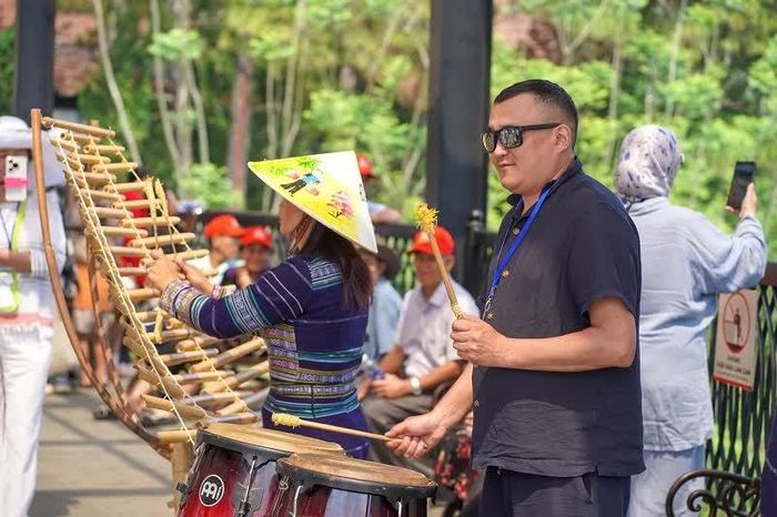Du khách nước ngoài thích thú trải nghiệm nhạc cụ dân tộc tại Khu du lịch Thung lũng tình yêu.