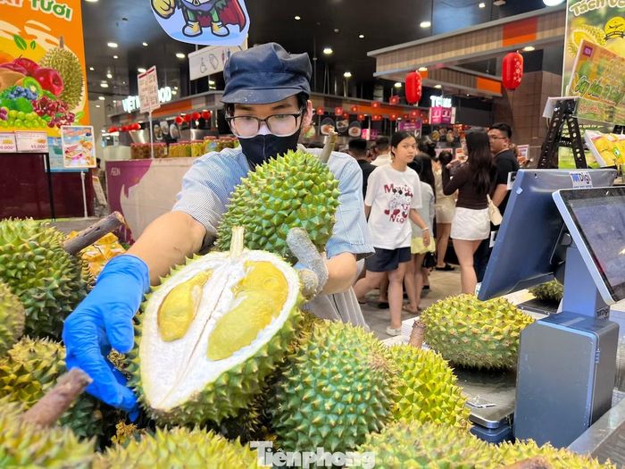 Nhân viên siêu thị khui sầu riêng chào hàng đến người tiêu dùng.