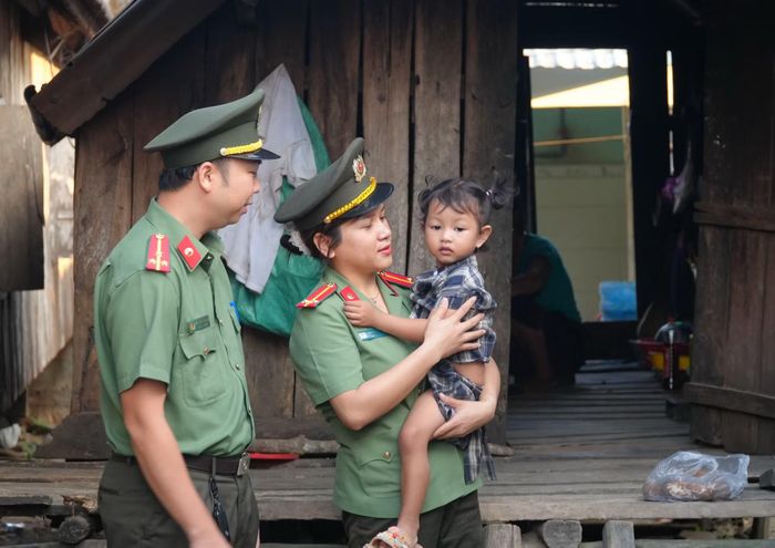 Nữ Trung úy Ksing Hờ Yên cùng đồng đội Công an xã Ea Bá đến thăm một đứa trẻ ở buôn Quen.