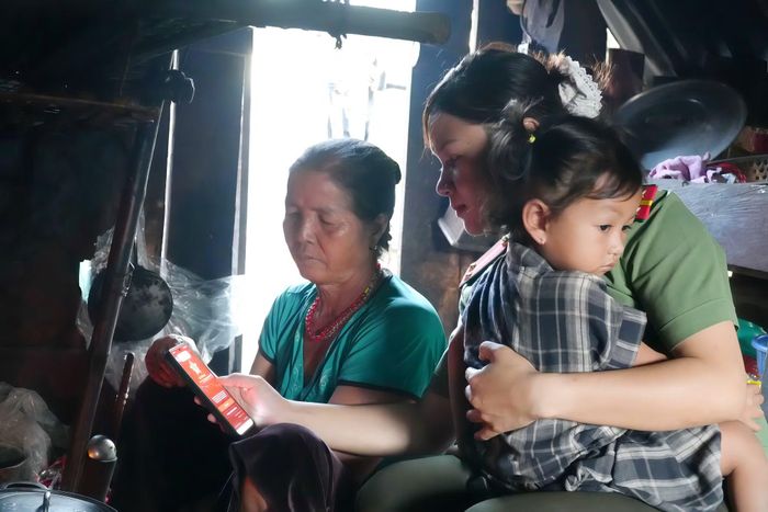 Cán bộ Công an xã Ea Bá hướng dẫn bà Niê Hờ Bôi, trú tại buôn Quen thao tác sử dụng VNeID trên điện thoại di động.