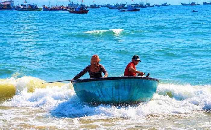 Ngư dân Trần Văn Vang (bên phải) chèo thuyền thúng vào bán hải sản. Ảnh: CĐ.