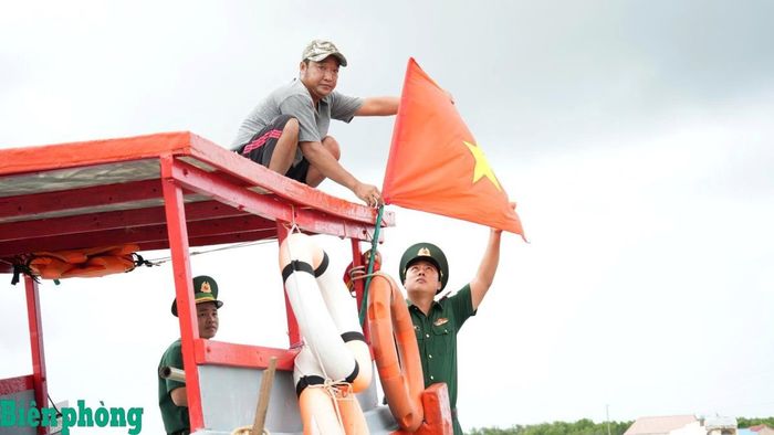 Đồn Biên phòng Đất Mũi hướng dẫn ngư dân treo cờ Tổ quốc trước khi ra khơi. Ảnh: Hoàng Tá