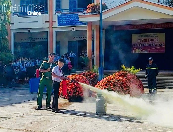 Học sinh thực hành sử dụng bình chữa cháy xách tay để dập lửa.