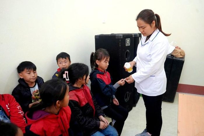 Nhân viên y tế phát thuốc tận tay và trực tiếp hướng dẫn học sinh uống thuốc. Ảnh: TL
