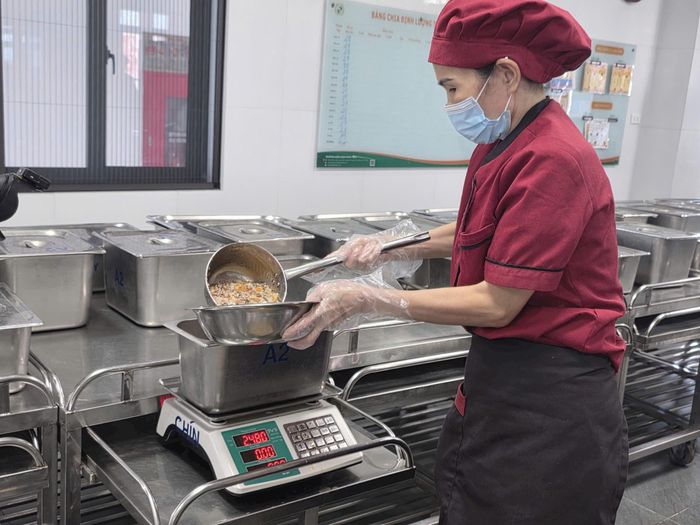 Nhân viên nhà bếp trường Mầm non Phúc Lộc chia đồ ăn theo định lượng cho từng lớp. Ảnh:MK