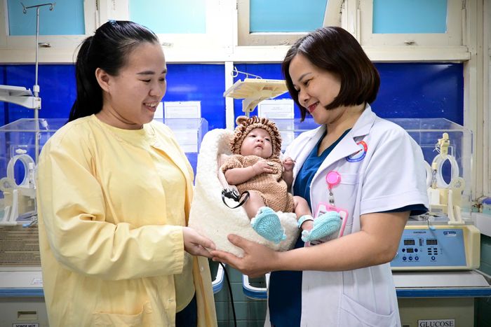 Bác sĩ Hân trìu mến trao bé sơ sinh cho sản phụ Nhàn vì con được về nhà sau 4 tháng nằm viện.