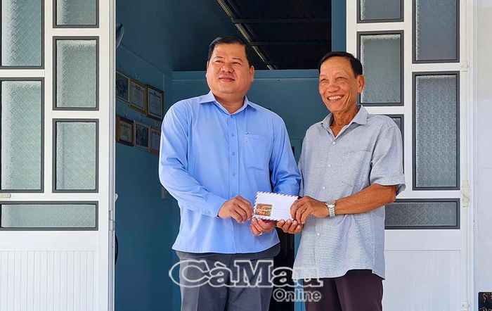 Ông Ðặng Minh Pháp, Chủ tịch UBND xã An Trạch, trao hỗ trợ một phần kinh phí cho ông Trương Công Ơn (bên phải) trong lễ bàn giao nhà.