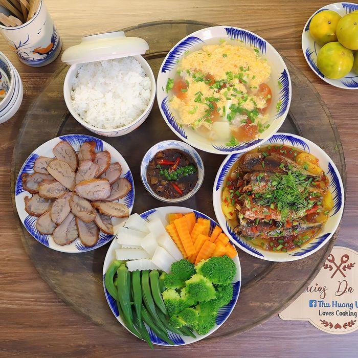 Mâm cơm có món cá nục sốt cà, xá xíu má đào, rau củ luộc chấm kho quẹt, canh trứng vân mây.