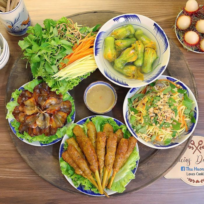 Mâm cơm có món nộm sứa xoài xanh, nem lụi bọc sả, cá chỉ vàng chiên, canh hoa bí nhồi thịt.