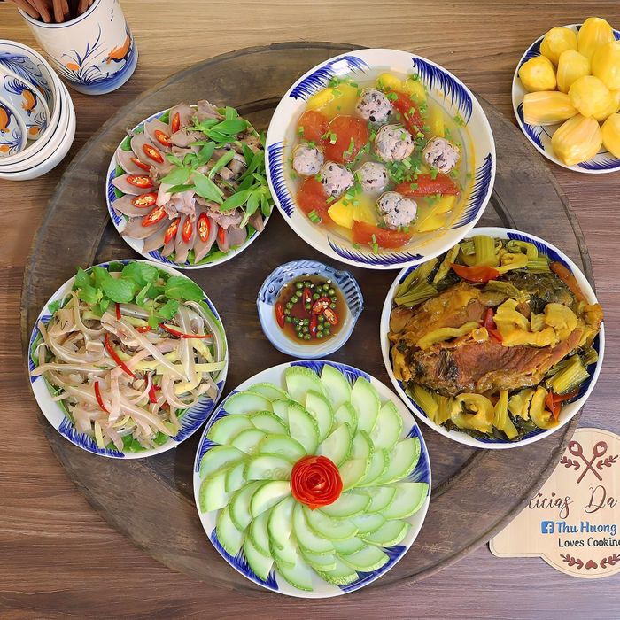 Mâm cơm có món cá trắm kho dưa, chạo tai heo xoài xanh bóp thấu, lưỡi heo luộc, canh chua mọc nấu dứa, dưa chuột mèo.