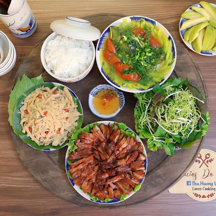 Mâm cơm mùa hè gồm có món thịt xá xíu, nem thính lá sung, canh chua cá nấu dọc mùng, rau sống rau thơm.