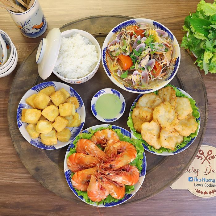 Mâm cơm có món tôm sú hấp nước dừa, chả mực, đậu phụ rán, canh chua ngao nấu dứa.