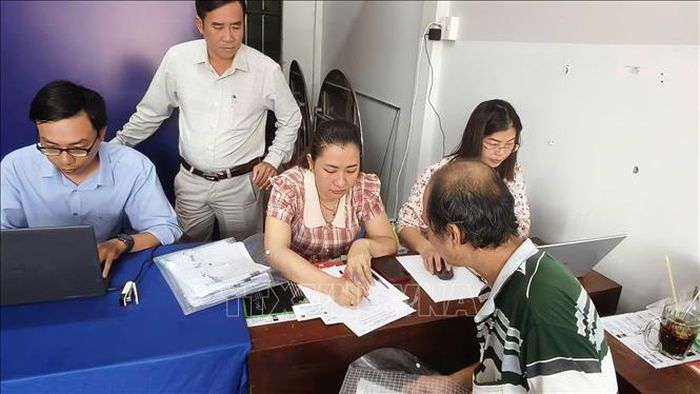 Cán bộ bộ phận đất đai viết giấy tay hướng dẫn người dân từng bước để chuẩn bị hồ sơ làm thủ tục hành chính.