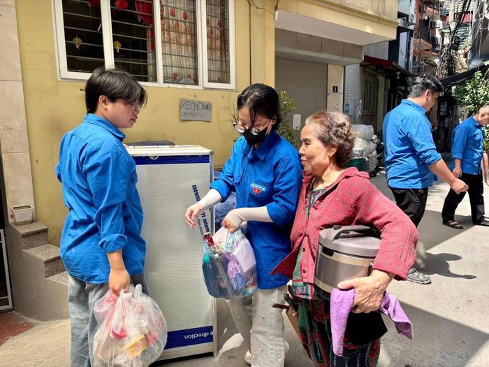 Thanh niên tình nguyện mang các vật dụng gia đình di chuyển cùng người dân