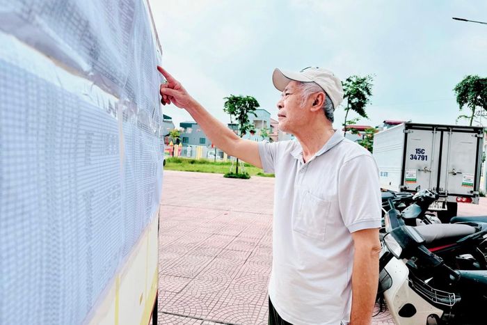 Người dân xã Nam Phù theo dõi thông tin công bố thu hồi đất phục vụ dự án đường Vành đai 3,5. Ảnh: Phương Xuyến