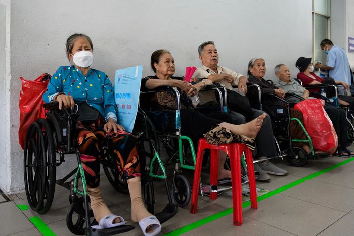  Ở khu vực chờ của xe lăn, bà Đặng Thị The (64 tuổi, ngoài cùng bên trái) ngồi lặng chờ đến lượt lấy thuốc sau ca mổ cột sống cách đây 2 tháng. Từ 3h sáng, bà và em gái đã có mặt tại bệnh viện để lấy số tái khám và may mắn nhận được số thứ tự 4. “Đi khám Chợ Rẫy nhiều lần rồi mà hôm nay tôi vẫn thấy đông bất ngờ”, bà nói. 