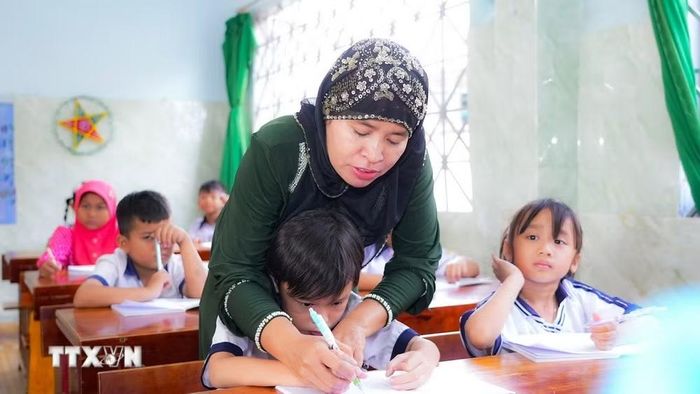 Cô Thị Saly Has, giáo viên người dân tộc Chăm của Trường Tiểu học Lê Văn Tám, tận tình hướng dẫn học sinh luyện viết tiếng Việt. (Ảnh: Minh Phú/TTXVN)