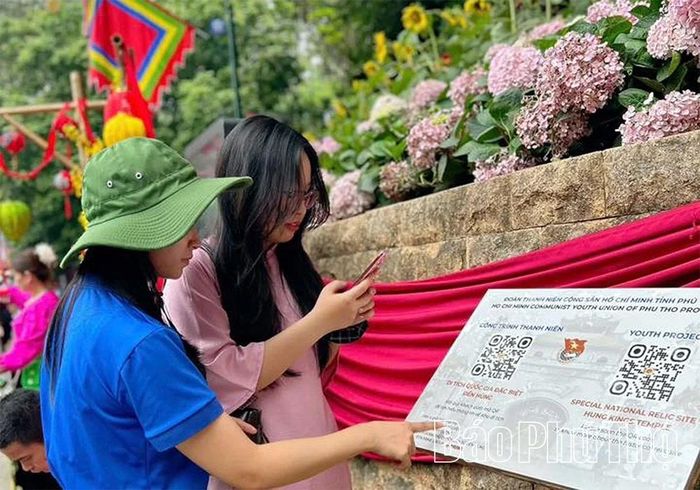 Các ĐVTN Trường Đại học Hùng Vương hướng dẫn du khách quét mã QR tại Khu di tích lịch sử Đền Hùng để tìm hiểu các thông tin chung về lễ hội khi hành hương về Đền Hùng năm 2026.