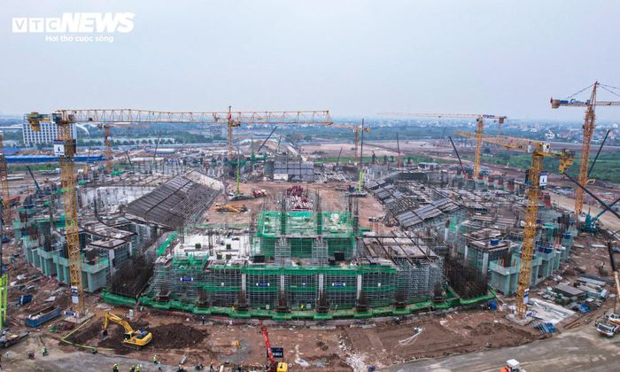 Nhiều xe cẩu, máy xúc, xe tải hoạt động liên tục phục vụ thi công phần kết cấu và vận chuyển vật liệu. Đến nay, phần móng khu vực sân chính cơ bản hoàn thiện. Dự án hiện bước sang giai đoạn thi công phần thân và hệ thống khán đài.