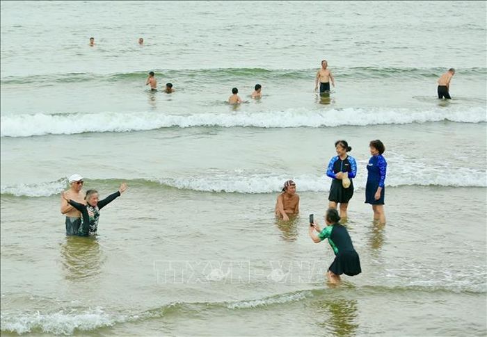 Sau nỗ lực dọc dẹp môi trường của chính quyền địa phương, du khách thích thú khi tắm biển tại bãi biển Hải Tiến. Ảnh: Khiếu Tư/TTXVN