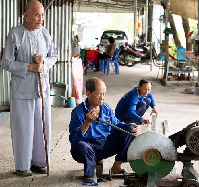 Các thành viên Tổ từ thiện Ban Trị sự Phật giáo Hòa Hảo xã Vĩnh An cắt sắt tạo khung nhà Đại đoàn kết.